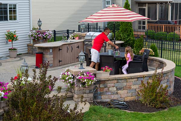 A grey, brick-faced retaining wall surrounding a backyard patio.