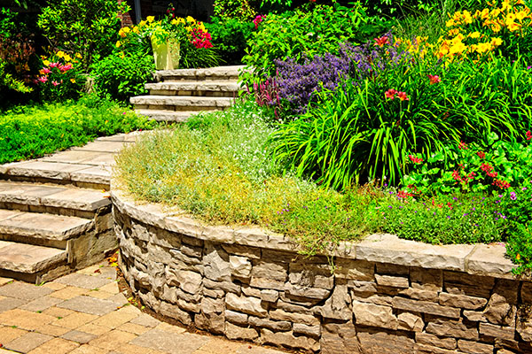 A retaining wall, faced with flagstone, enclosing a flower garden.