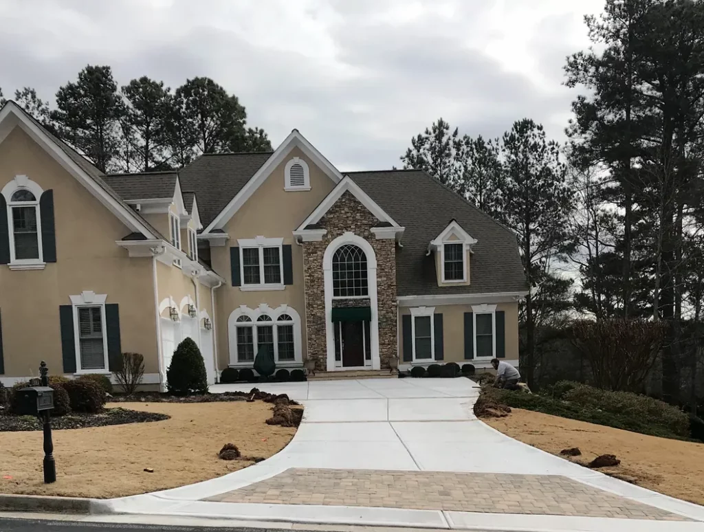 A wide concrete driveway with a paver accent leading up to a luxury home.